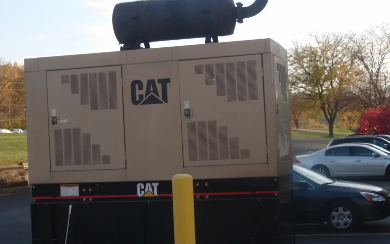 How Big of a Standby Generator Should I Buy? A Caterpillar diesel generator set in a beige enclosure beside a parking lot