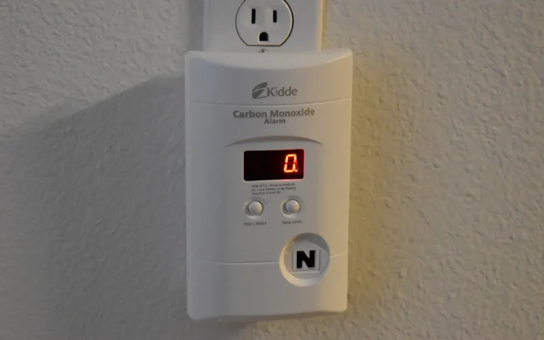 A plug-in carbon monoxide detector with a digital display mounted on a wall outlet
