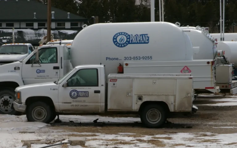 A propane delivery truck and a service pickup parked in a supplier's yard