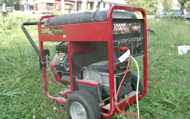 A red open-frame portable generator standing on grass with a cord plugged in
