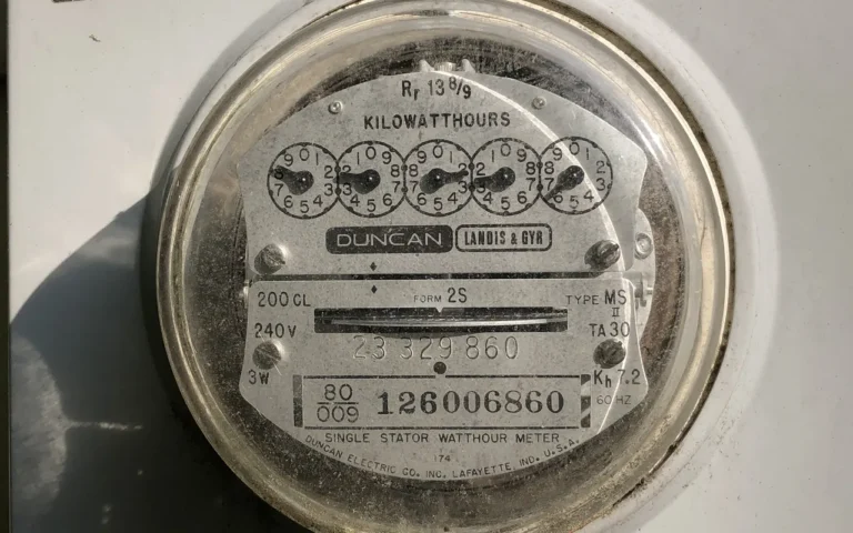 A residential electric meter mounted on the outside wall of a house