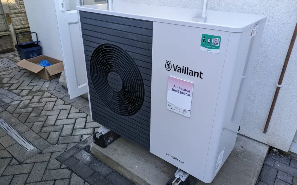 An air source heat pump outdoor unit standing beside a house
