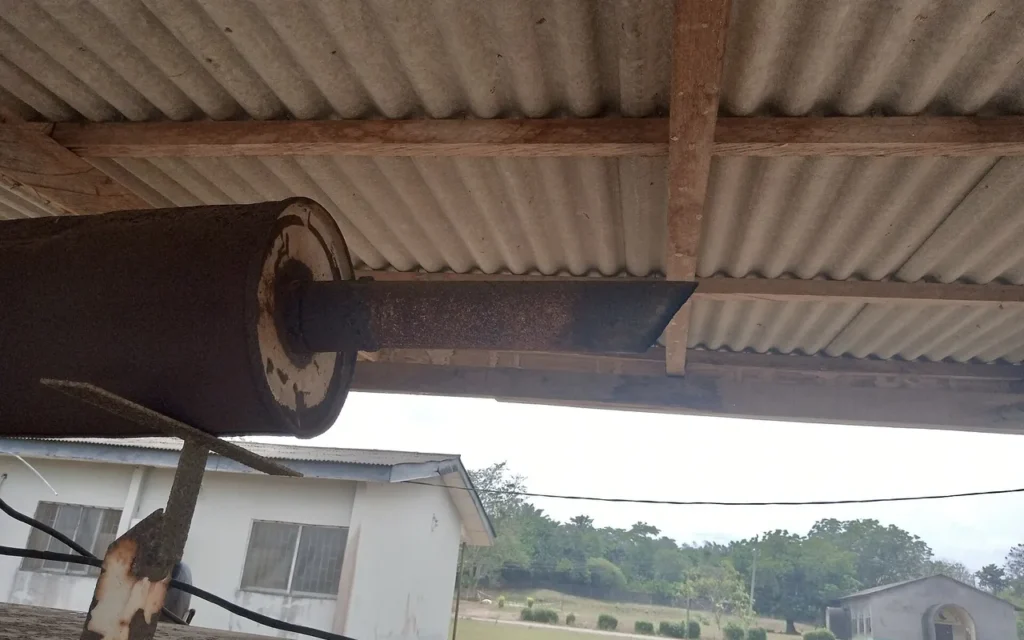 A generator exhaust pipe running out under a corrugated roof