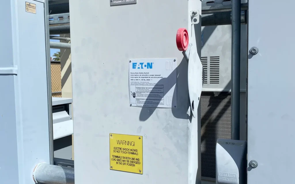 A gray outdoor disconnect switch mounted on a building wall