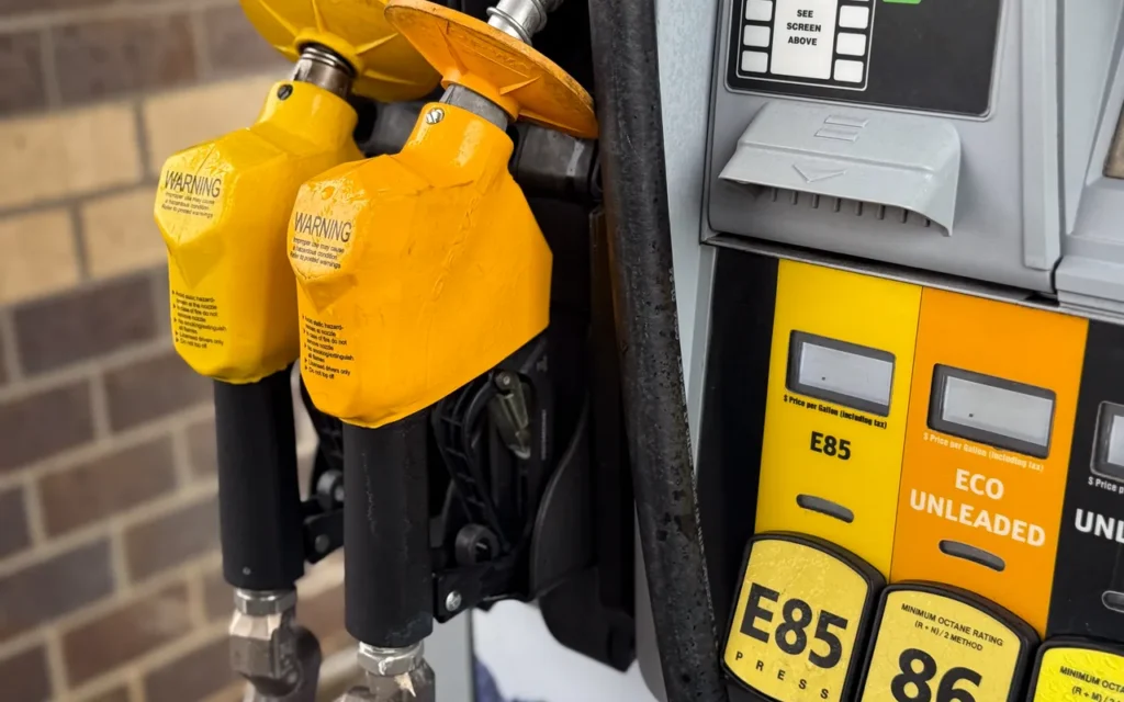 Yellow fuel pump nozzles at a gas station with E85 and unleaded grade labels